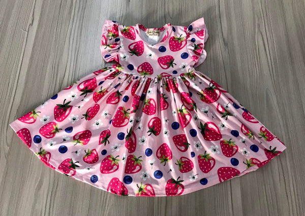 Pink twirly dress for girls with strawberry and blueberry print, ruffle sleeves, and a full skirt, laid flat on wooden floor.
